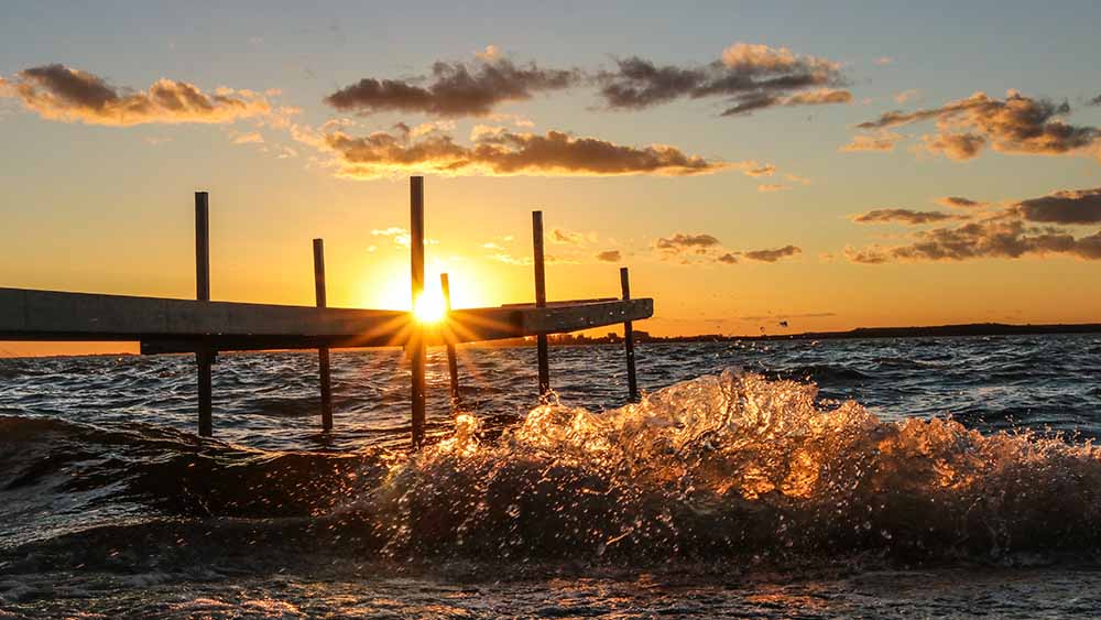 dock over lake in the summer evening with orange sunset in the background